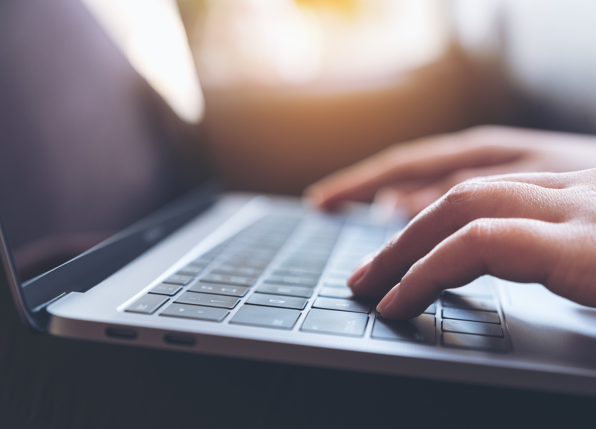 Laptop keyboard with hands typing