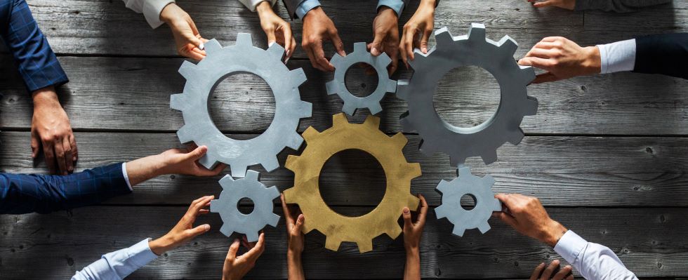 Many hands turning connected gears
